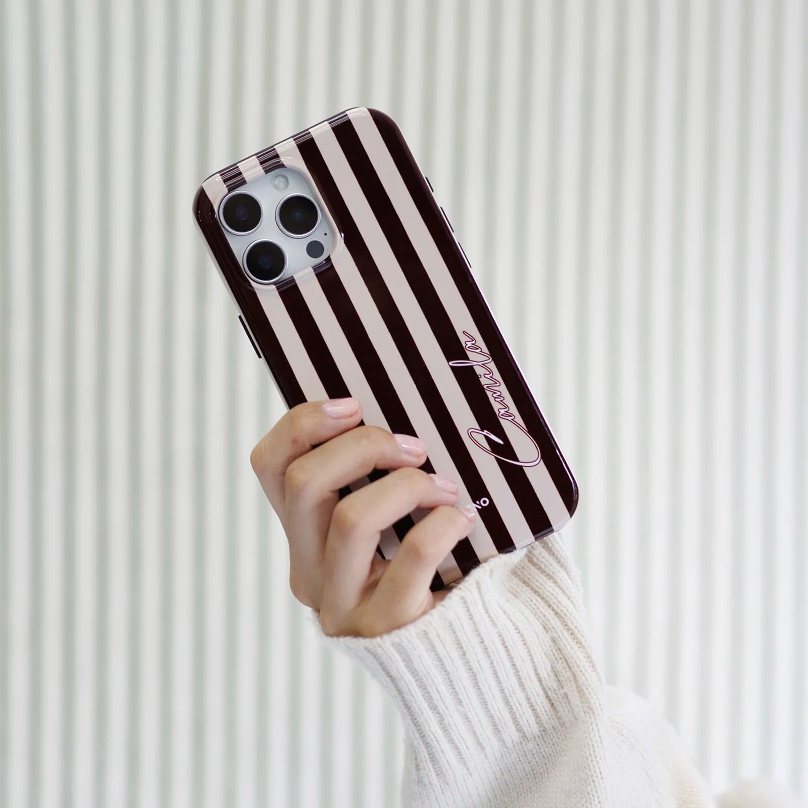 Merlot Stripes tough MagSafe case held in hand, personalized with name in Corvo calligraphy font